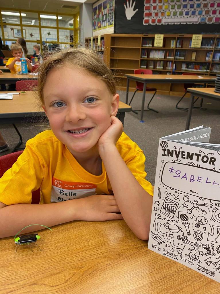Student smiles with camp invention booklet