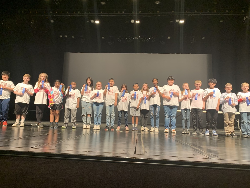 Columbia Elementary Math Bowl participants standing across the McHale Performing Arts stage holding their first place ribbons